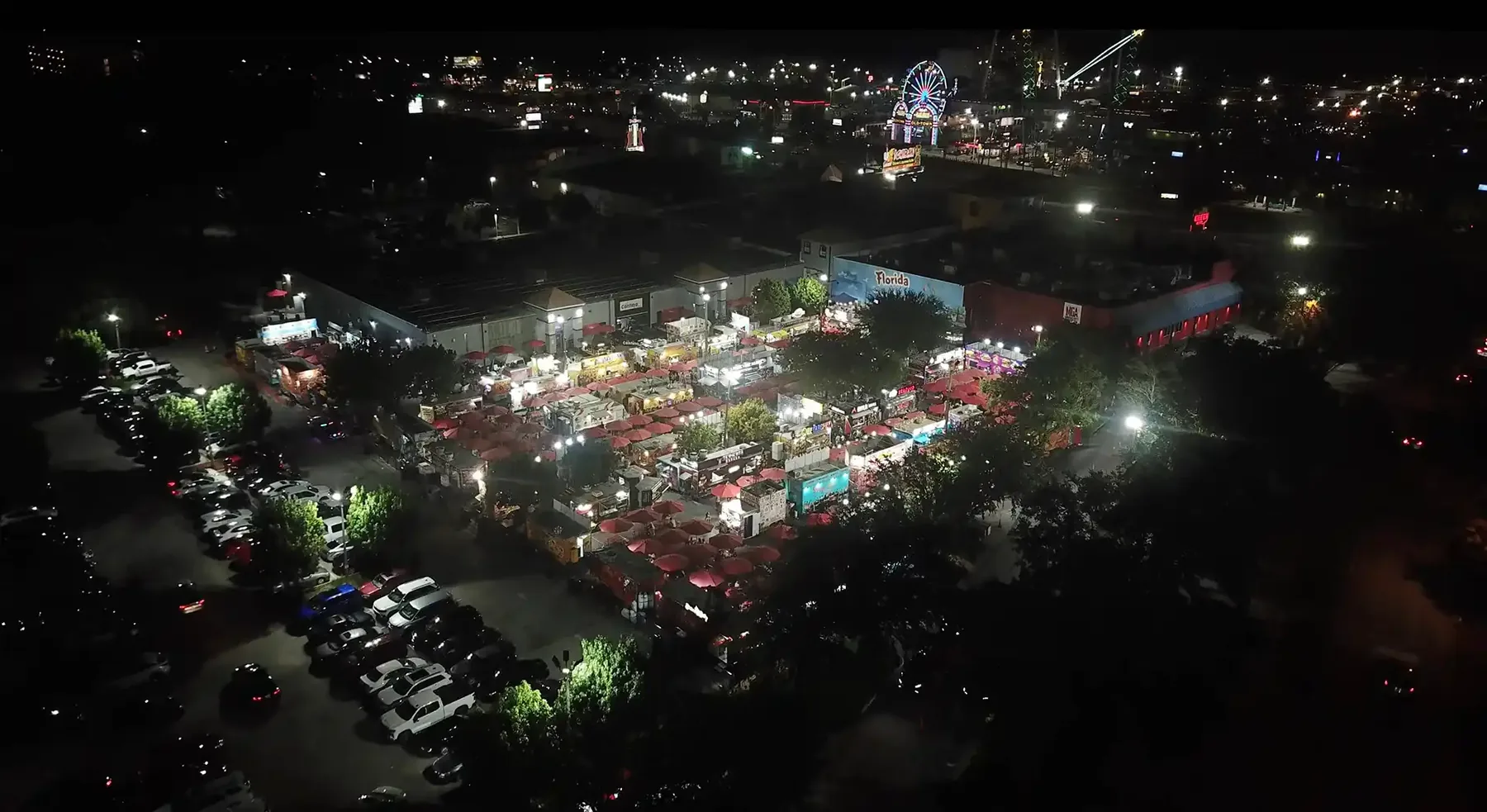The plaza from the air at night, the truck park glowing with string lights and the lot full of cars.