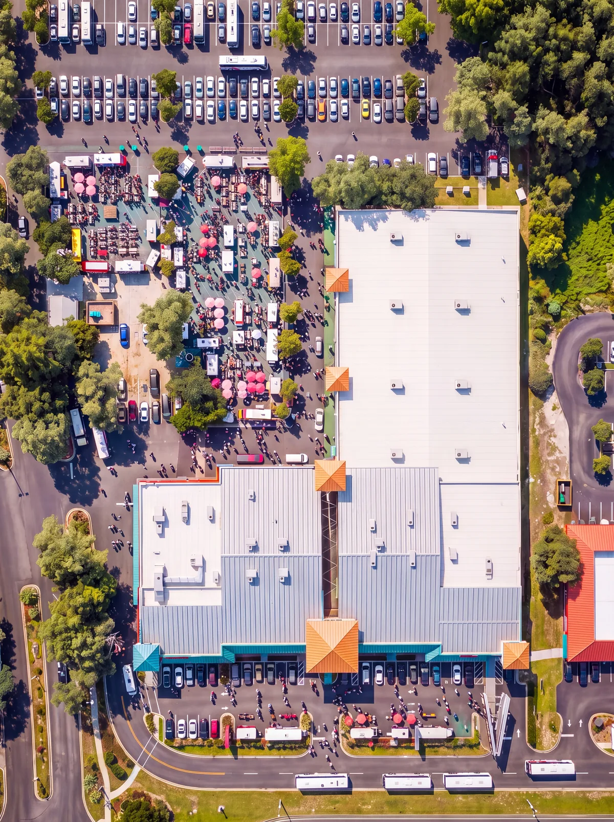 Aerial view of Visitors Plaza. The food truck park fills the top left, the market building runs down the right side, and Machine Gun America and Fun Games sit in the row along the bottom, with the parking lot and Highway 192 in front.